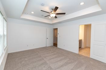 a bedroom with white walls and a ceiling fan
