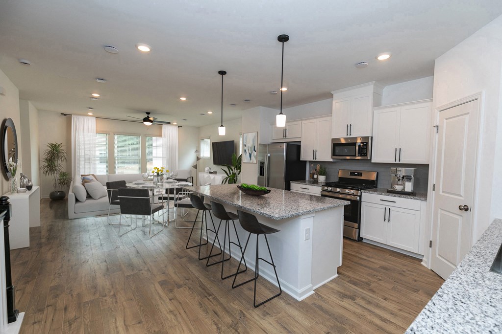 a kitchen and living room with hardwood floors and white cabinets