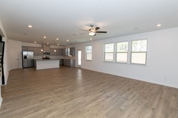 a living room and kitchen in a house with a ceiling fan