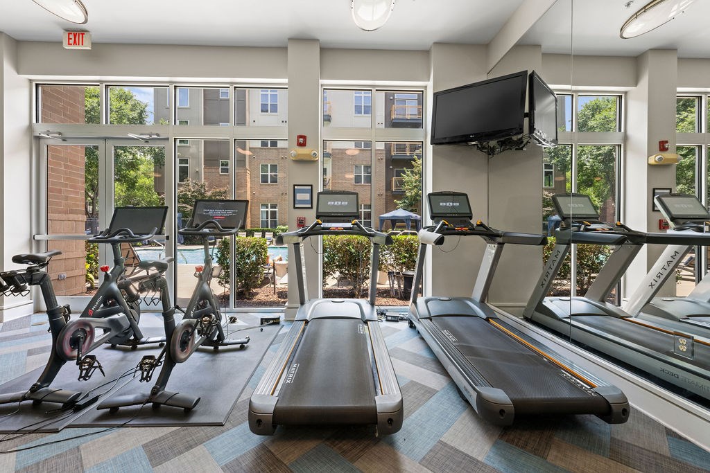 a gym with cardio equipment and windows at the apartments