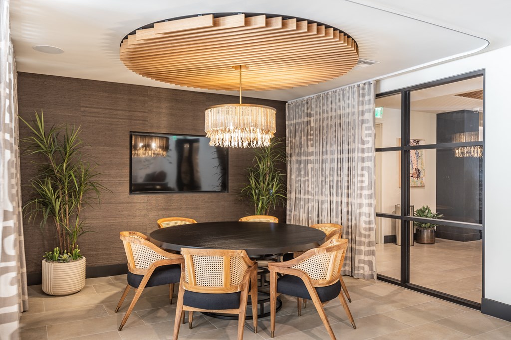 a round dining table with chairs and a chandelier in the middle of a room with