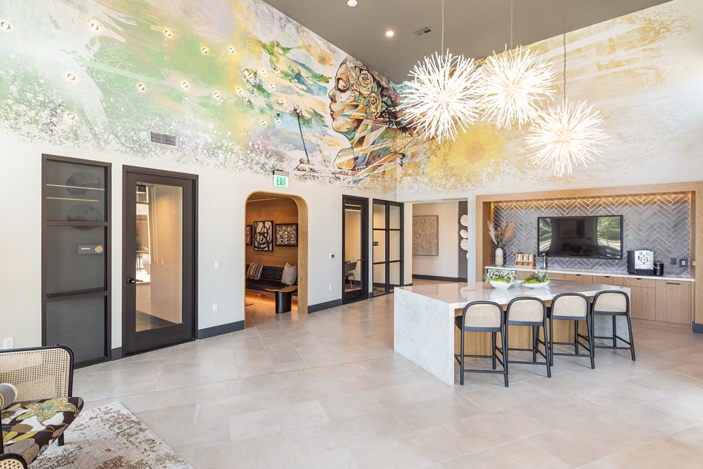 a lobby with a colorful mural on the ceiling and a kitchen with a bar and stools