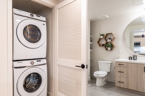 a bathroom with a washer and dryer next to a toilet and sink