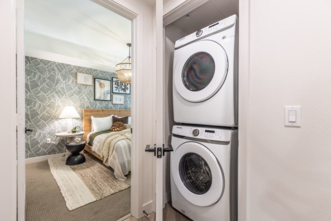 a bedroom with a washer and dryer and a bed in the background