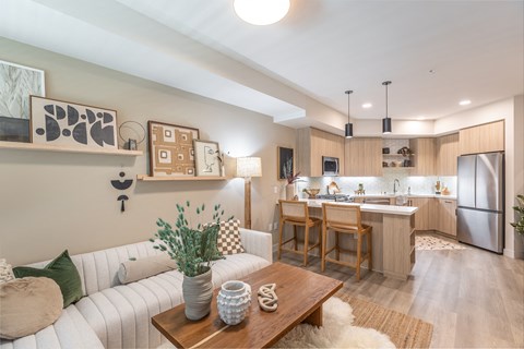a living room and kitchen with a white couch and wooden table