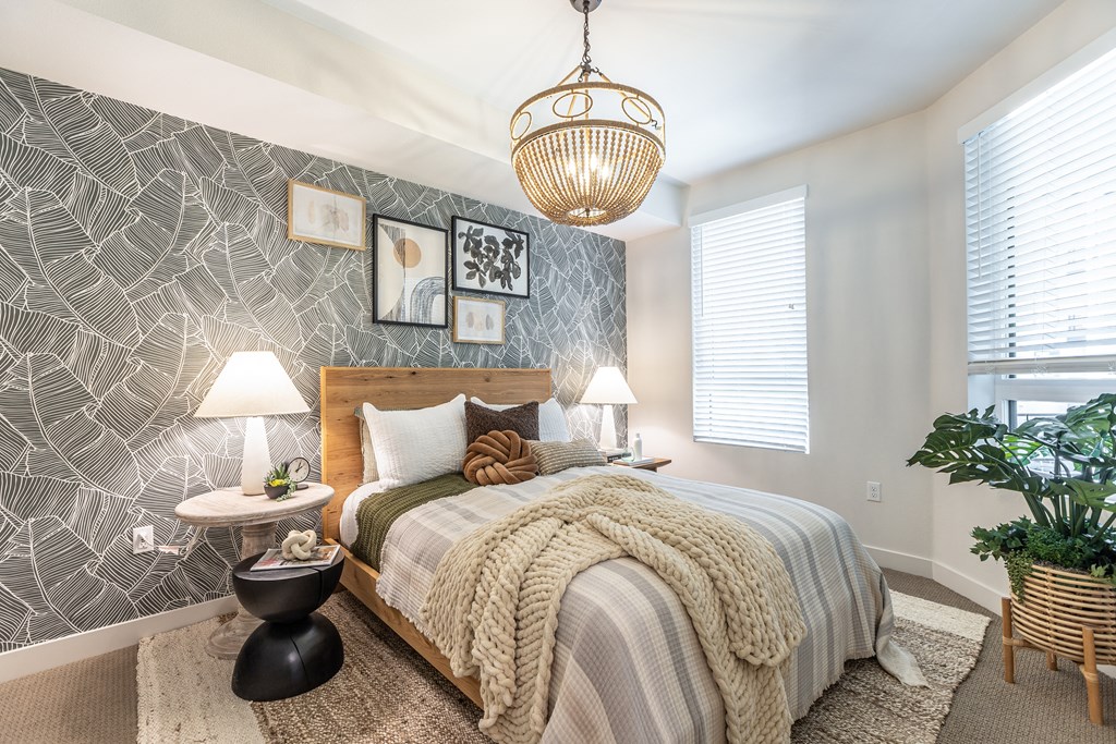 a bedroom with a gray and white patterned wallpaper and a large bed with a wooden head