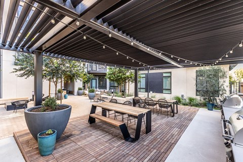 an outdoor patio with a picnic table and chairs and a grill