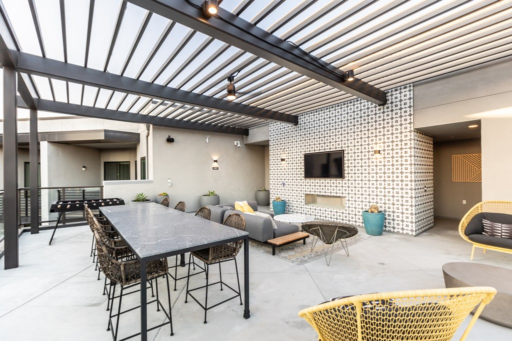 a patio with a long table and chairs and a television on the wall