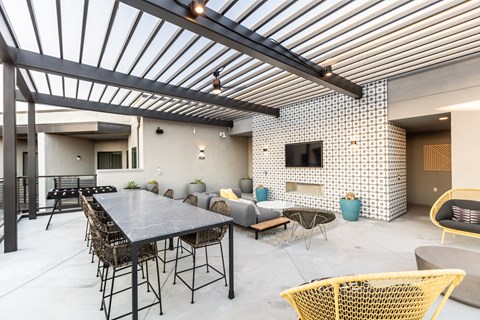 a patio with a long table and chairs and a television on the wall
