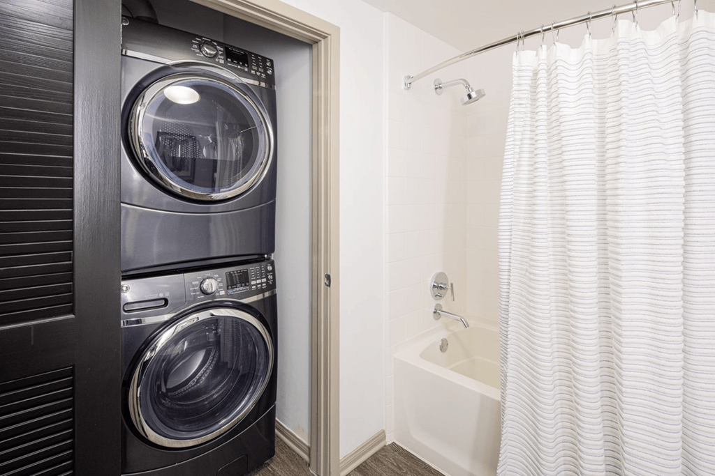 a washer and dryer in a bathroom with a shower and a tub