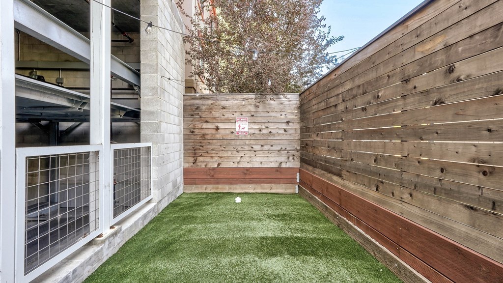 Fenced pet-friendly park with a designated waste disposal area, including a garbage can and waste bags for convenience.