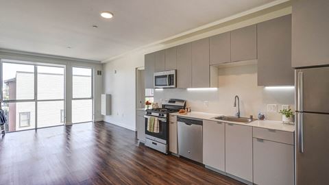 an empty kitchen with stainless steel appliances and a wooden floor