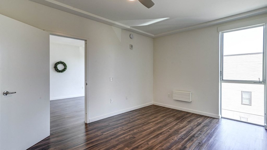 an empty living room with white walls and wood floors and ceiling fan