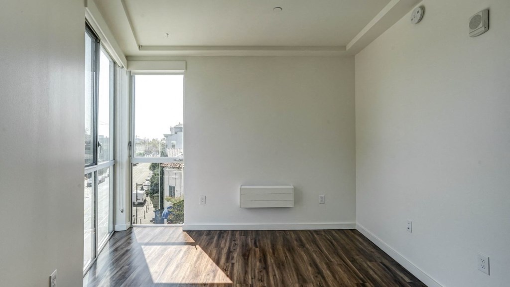 an empty living room with a heater on the wall