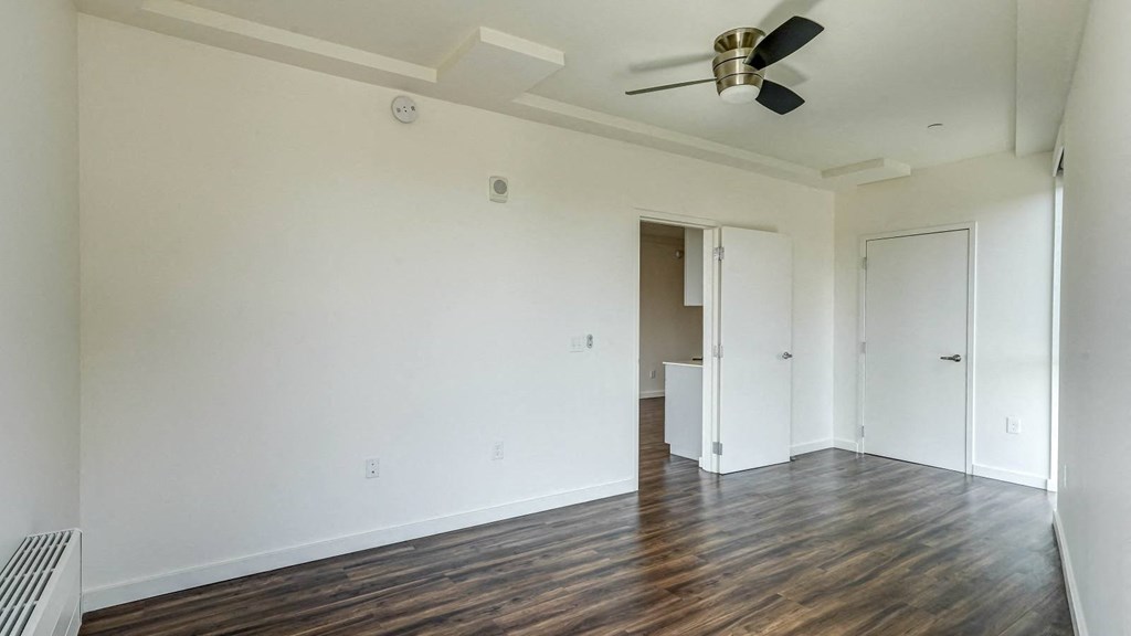 an empty living room with white walls and a ceiling fan