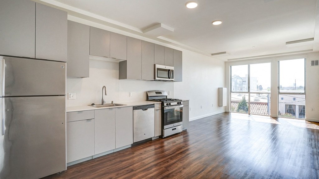 an empty kitchen with gray cabinets and stainless steel appliances