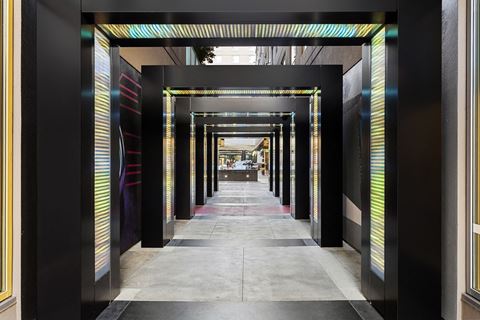 a long hallway with black doors and columns with colored stripes on the doors and walls
