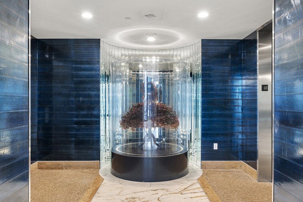 a glass shower in a blue bathroom with blue tile and a white marble floor