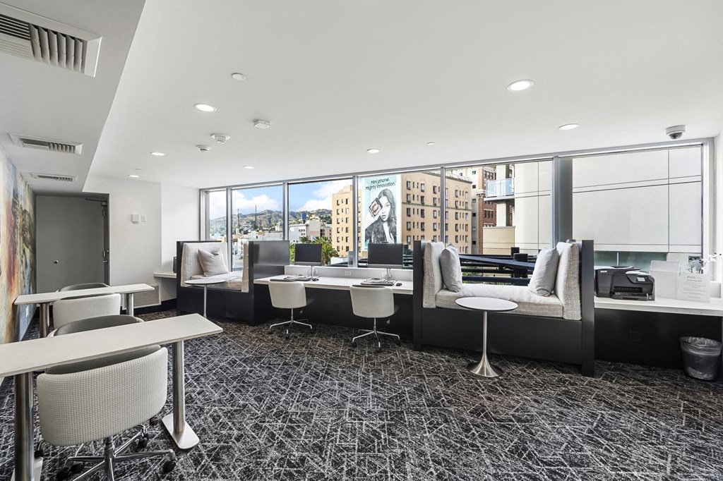 a lounge area with tables and chairs and a large window