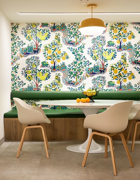 A dining room with a table and chairs in front of a wallpapered wall.