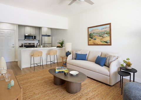 A living room with a couch, a coffee table, and a painting on the wall.