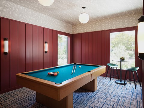 A pool table in a room with red walls.