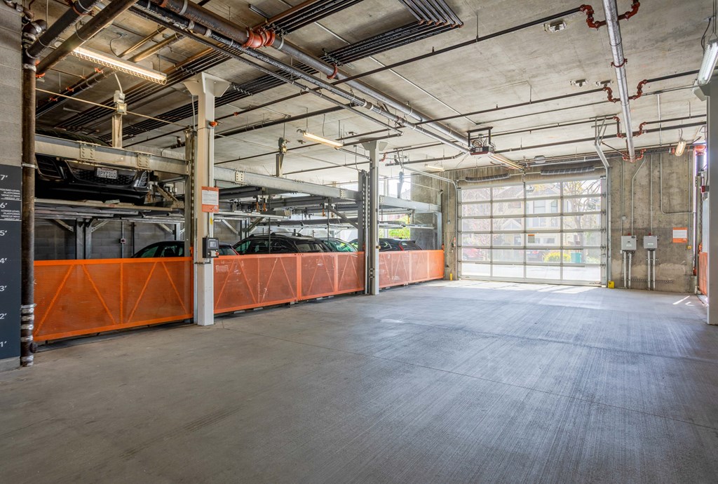 A large, empty warehouse with a concrete floor and orange safety barriers.