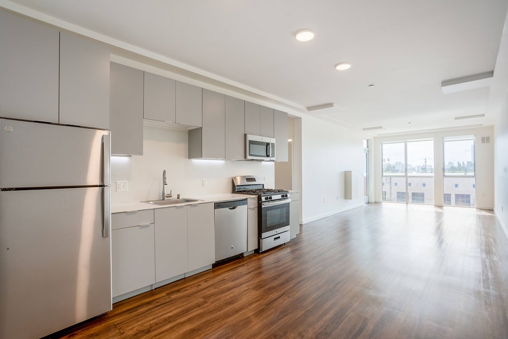 A modern kitchen with wooden floors and stainless steel appliances.