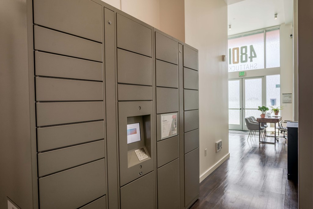 A room with a row of lockers and a table with chairs in the background.