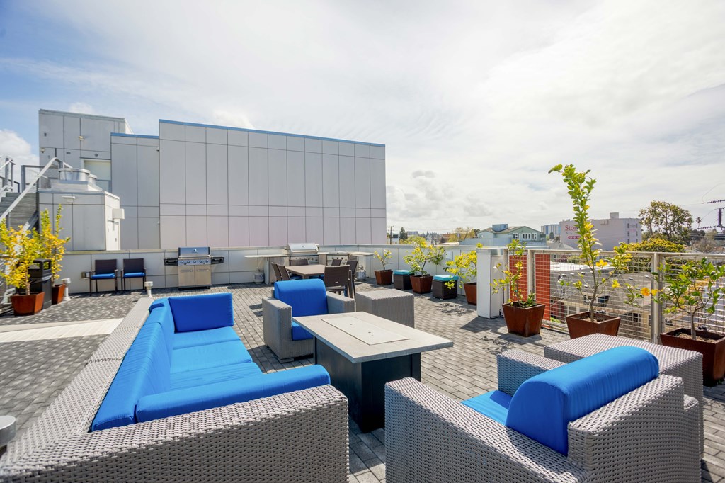 A modern outdoor seating area with blue cushions and grey wicker furniture.