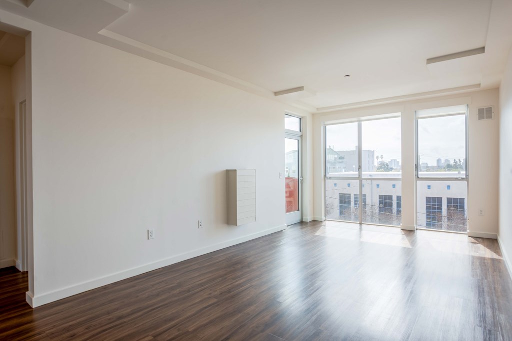 A room with white walls and wooden floors with a large window.