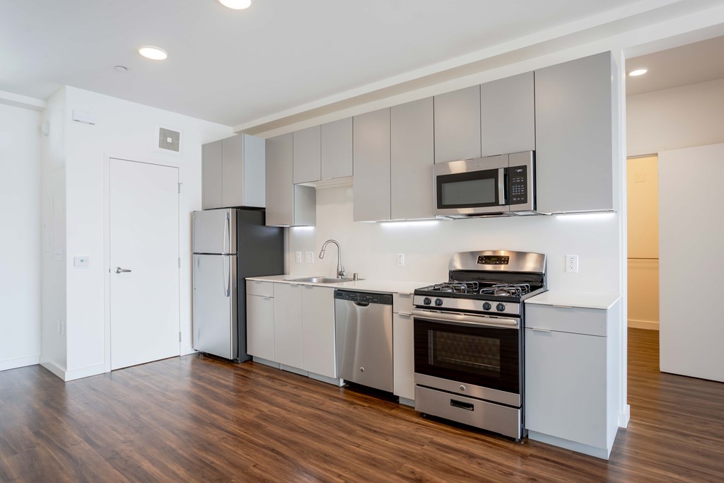 A modern kitchen with stainless steel appliances and wooden floors.