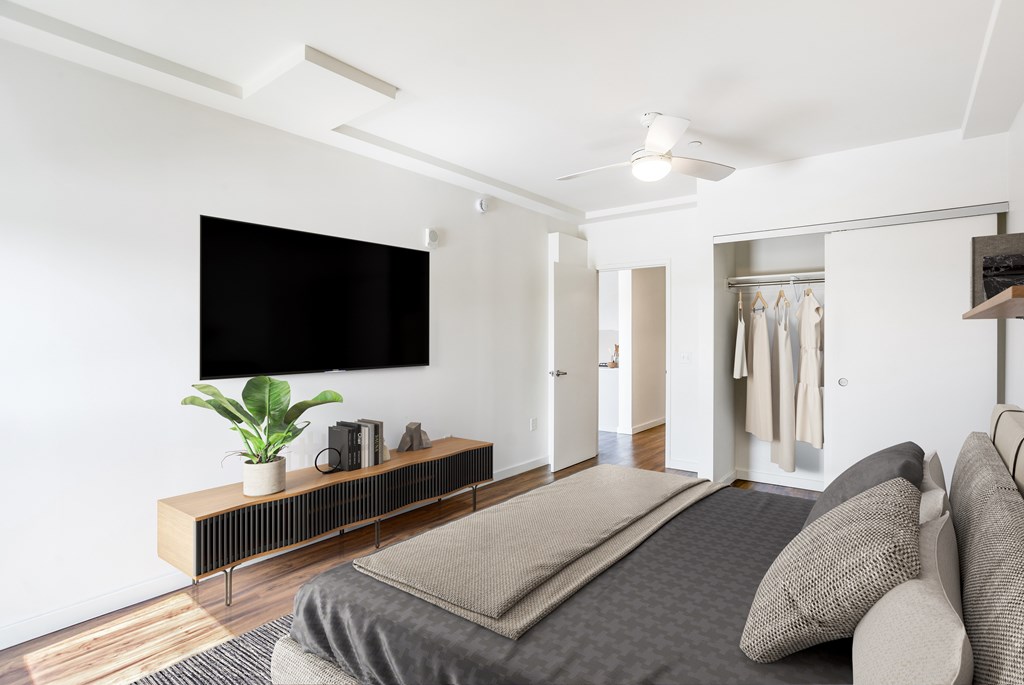 A modern bedroom with a large bed and a flat screen TV mounted on the wall.