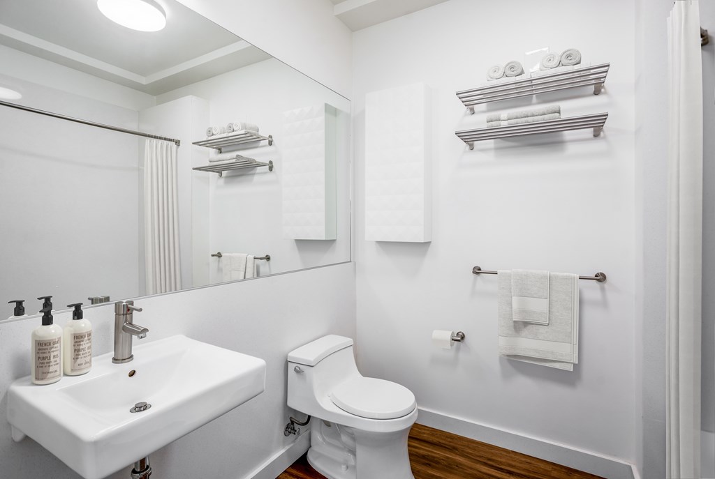 A white bathroom with a toilet, sink, and towel rack.