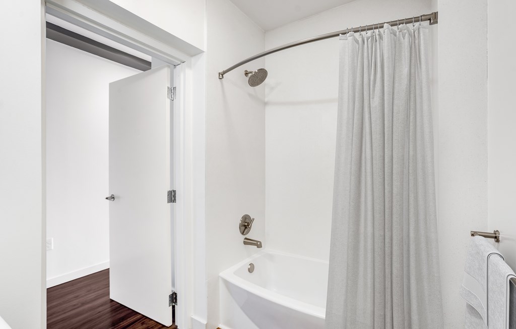 A white bathroom with a white tub and a white shower curtain.