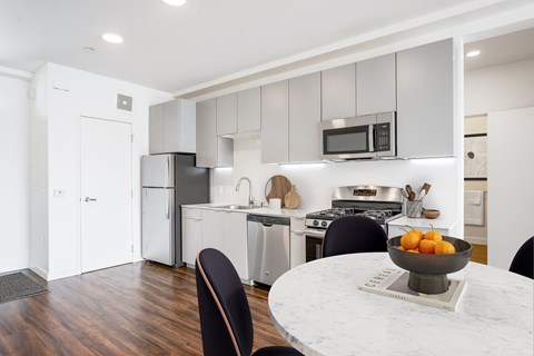 A kitchen with a table and chairs and a bowl of fruit on the table.