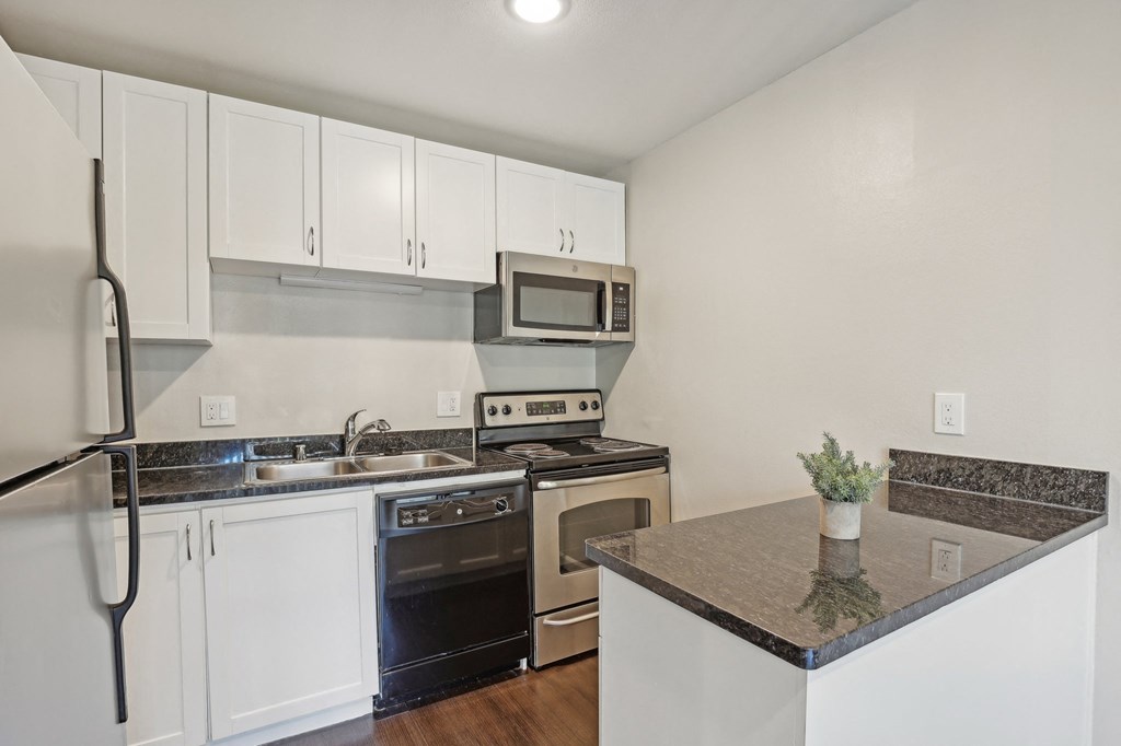 A kitchen with white cabinets and a black countertop.