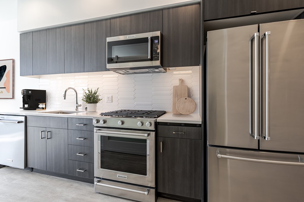 A modern kitchen with a stainless steel refrigerator and oven.