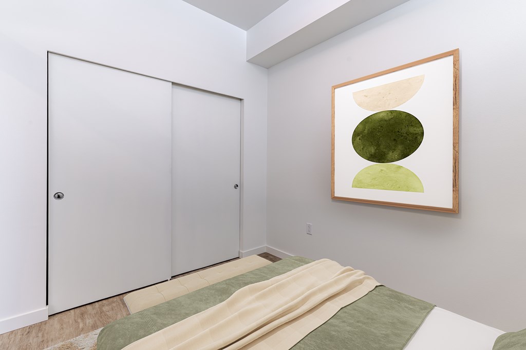 A bedroom with a bed, a wardrobe and a picture on the wall.