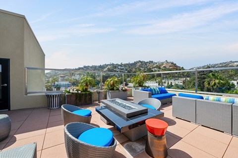 Rooftop sky lounge at 7950 West Sunset Apartments, featuring exterior chairs, sofas, and lush green plants, providing a serene and comfortable outdoor space for residents to enjoy