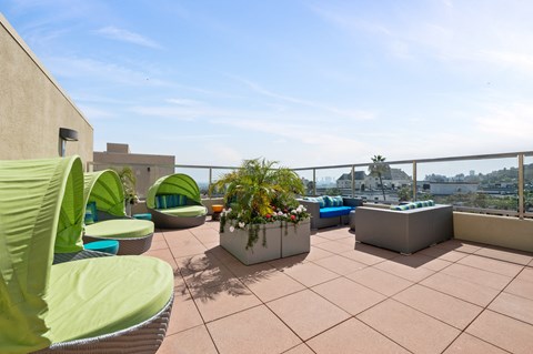 Rooftop lounge at 7950 West Sunset, featuring green sun-proof couches arranged around a floral centerpiece, offering a scenic and relaxing outdoor space for residents