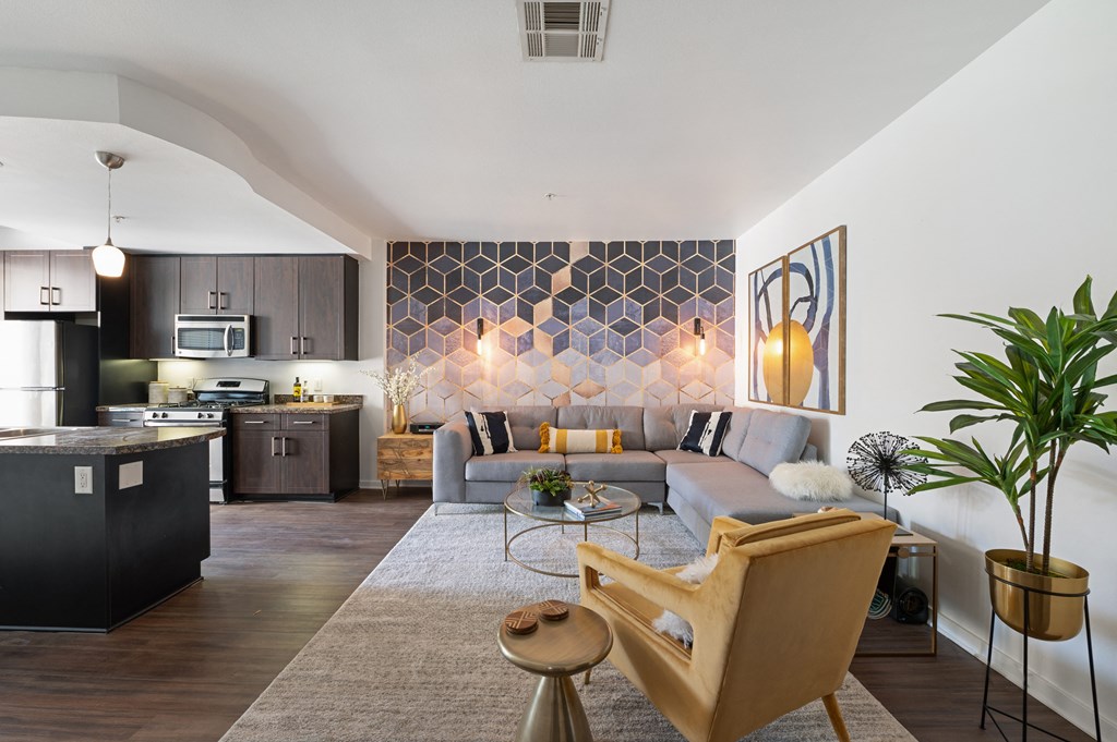 Modern open-concept living room and kitchen area with contemporary decor, including a large wall art piece