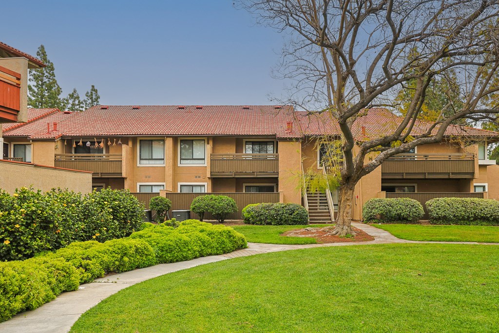 A tree stands in front of a building with a red roof.