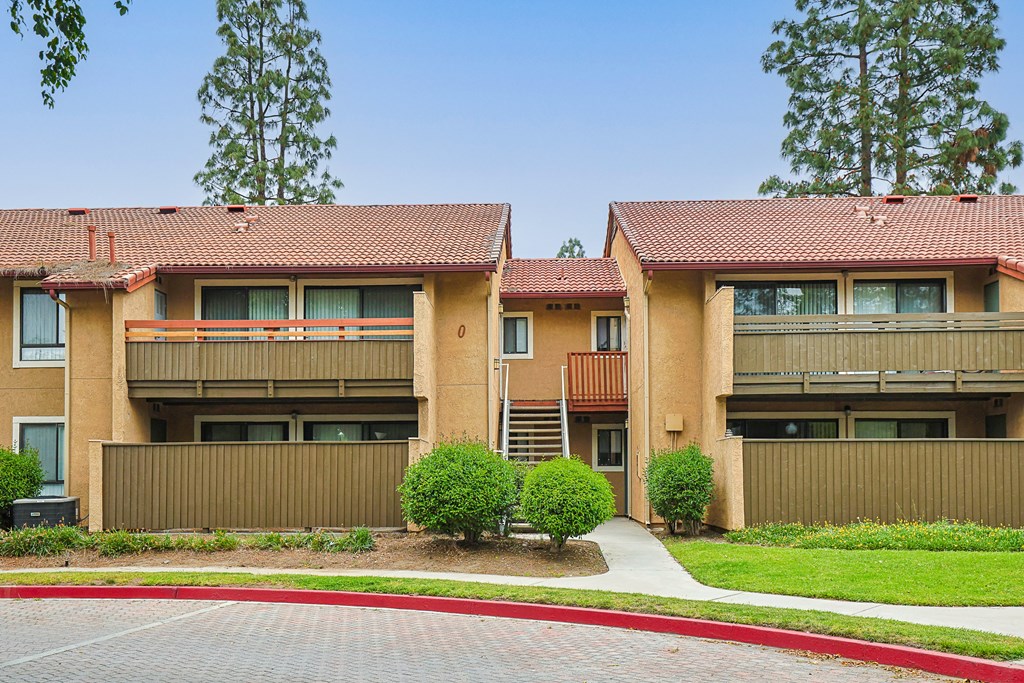 Apartment complex with red roofs and a brick driveway.
