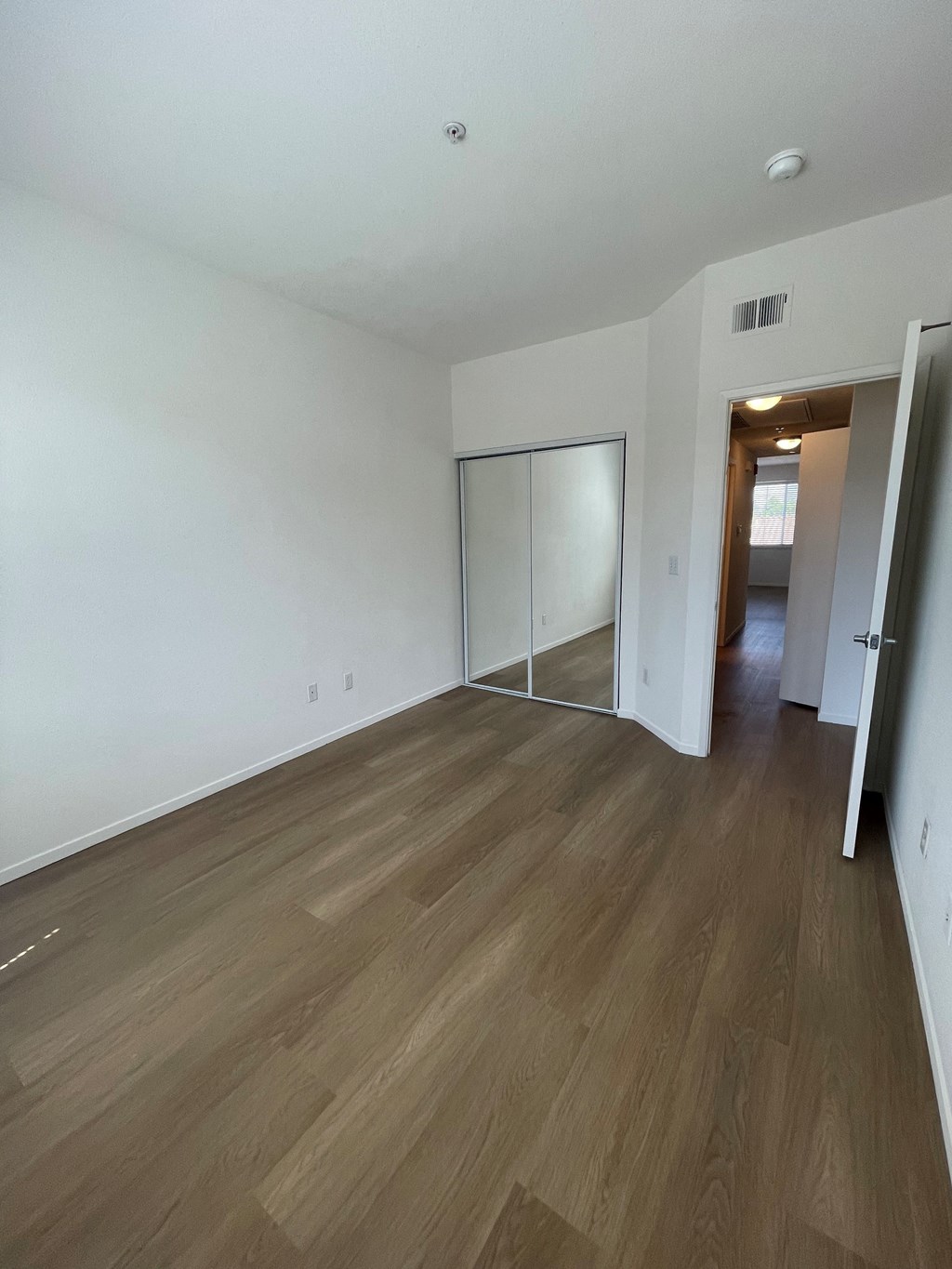 an empty living room with white walls and wood flooring