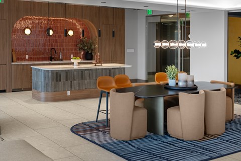 A modern dining area with a round table and orange chairs.