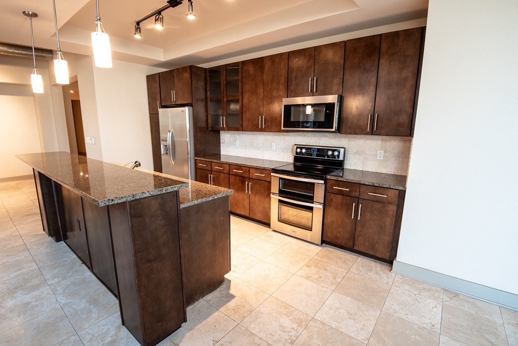 a kitchen with dark wood cabinets and a large island with granite countertops