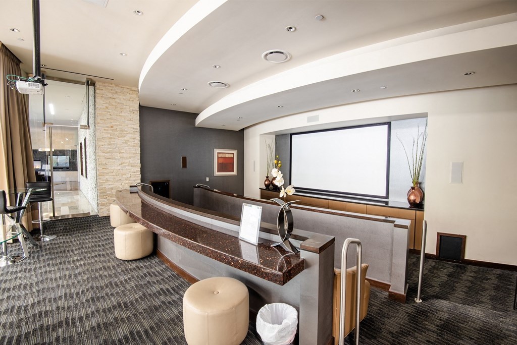 a reception area with a large screen tv on the wall and a long counter with stools
