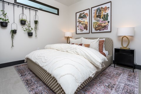 A bedroom with a large bed and two hanging potted plants.