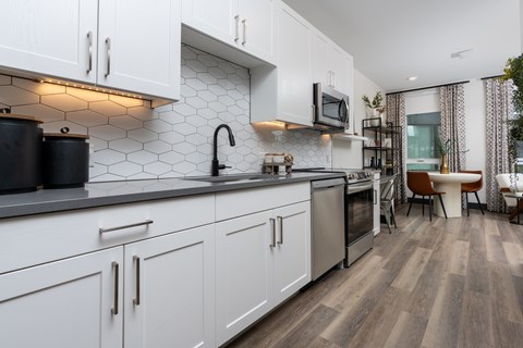 A modern kitchen with white cabinets and a black countertop.